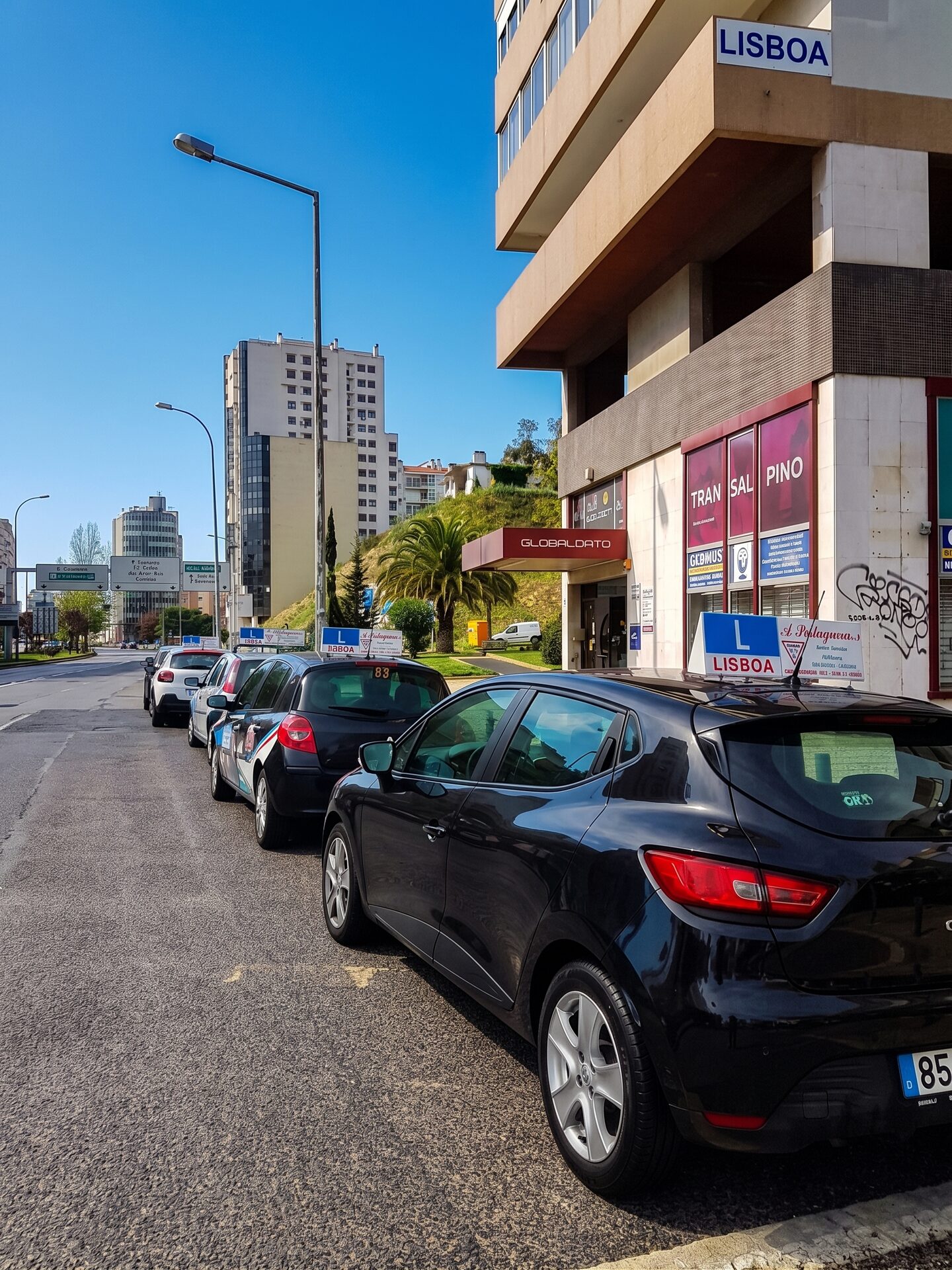 Carros de instrução da escola estacionados na rua, em Lisboa, com a insígnia A Portuguesa